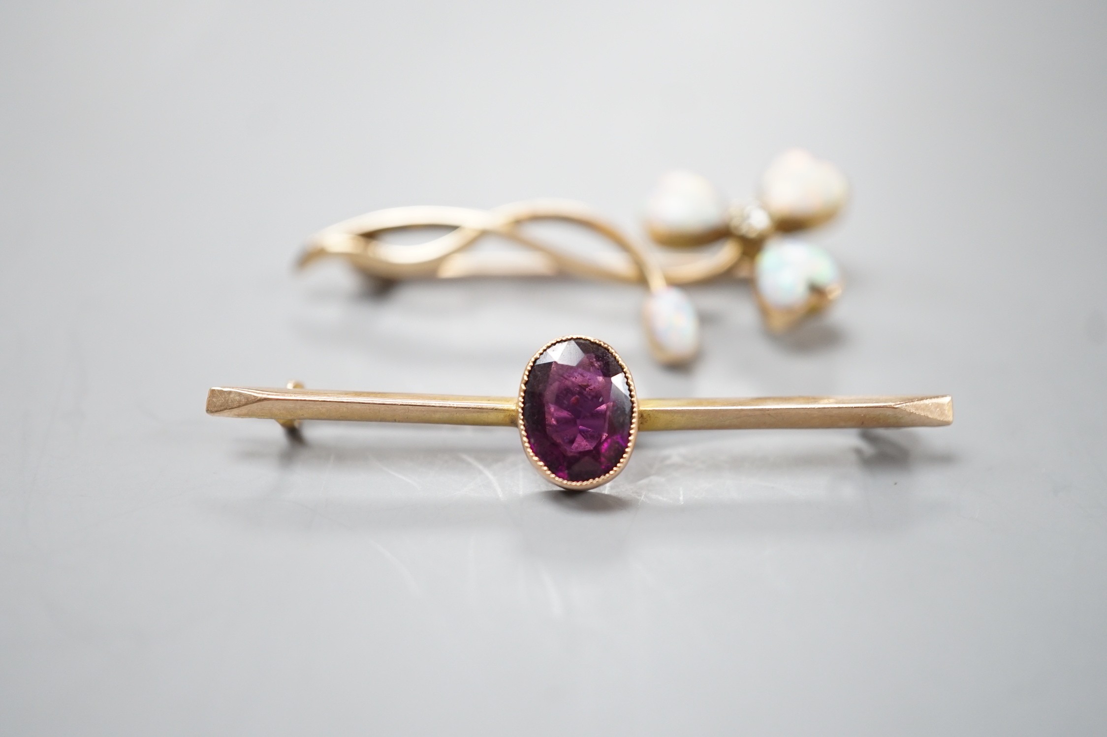 A yellow metal, four stone white opal including heart shape and diamond set foliate brooch, 40mm and a yellow metal and oval cut garnet set bar brooch, gross weight 5.4 grams.